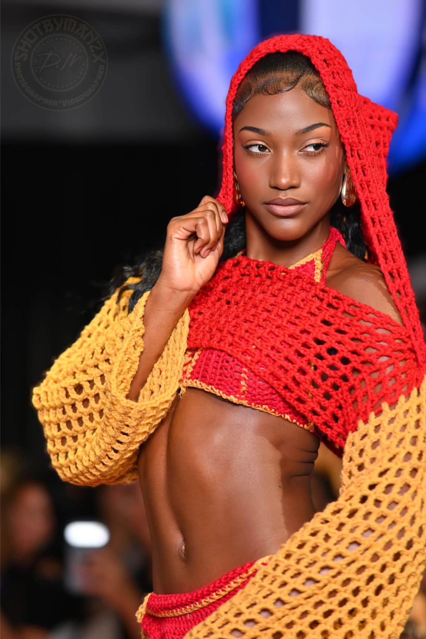 Model in a red and yellow crochet outfit with a hood