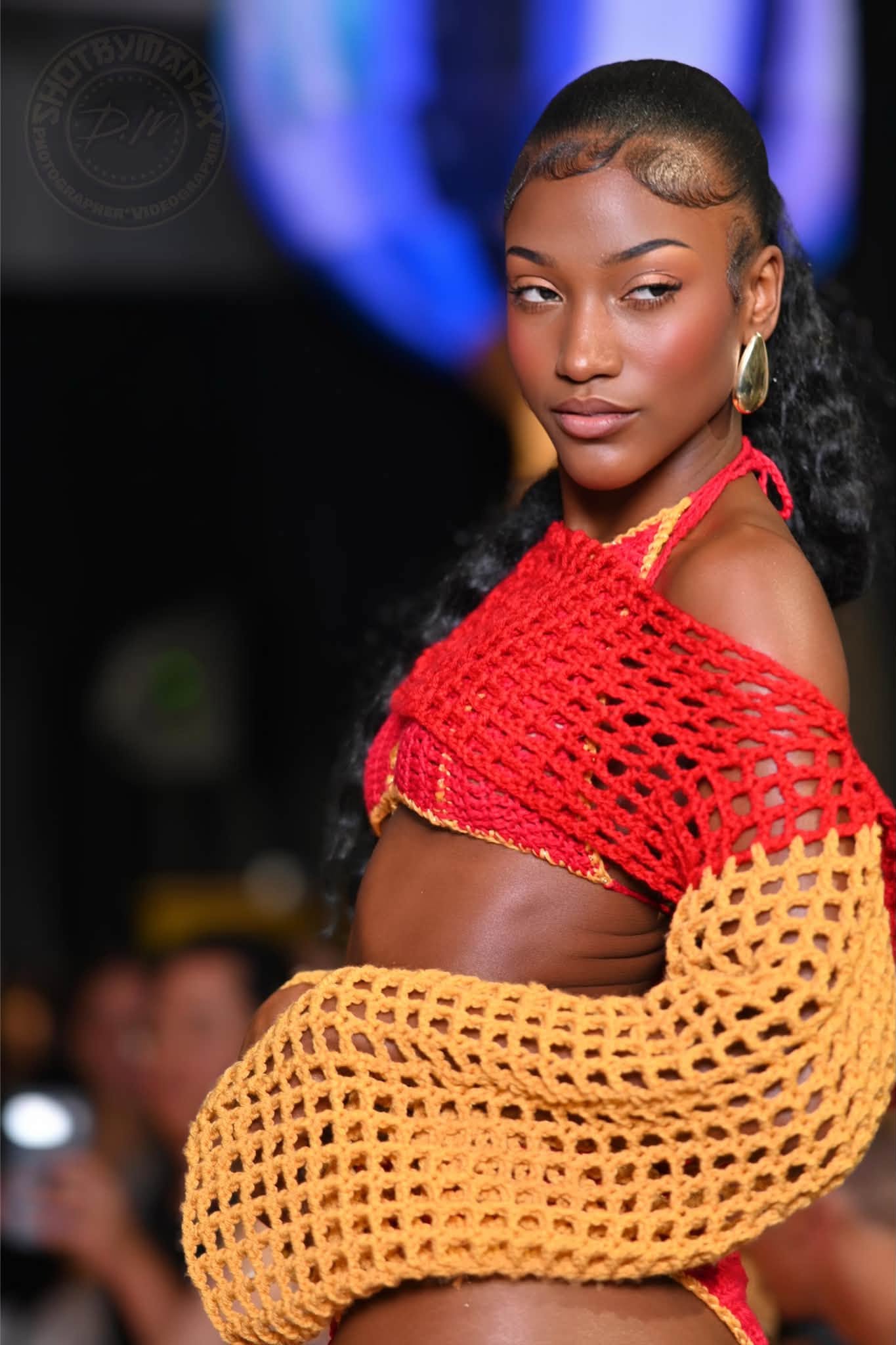 Portrait of a model wearing a red crochet top and yellow sleeves
