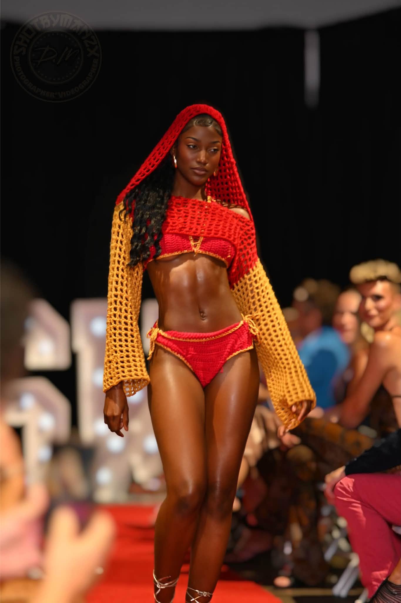 Full-length runway photo of a model in a red and yellow crochet outfit